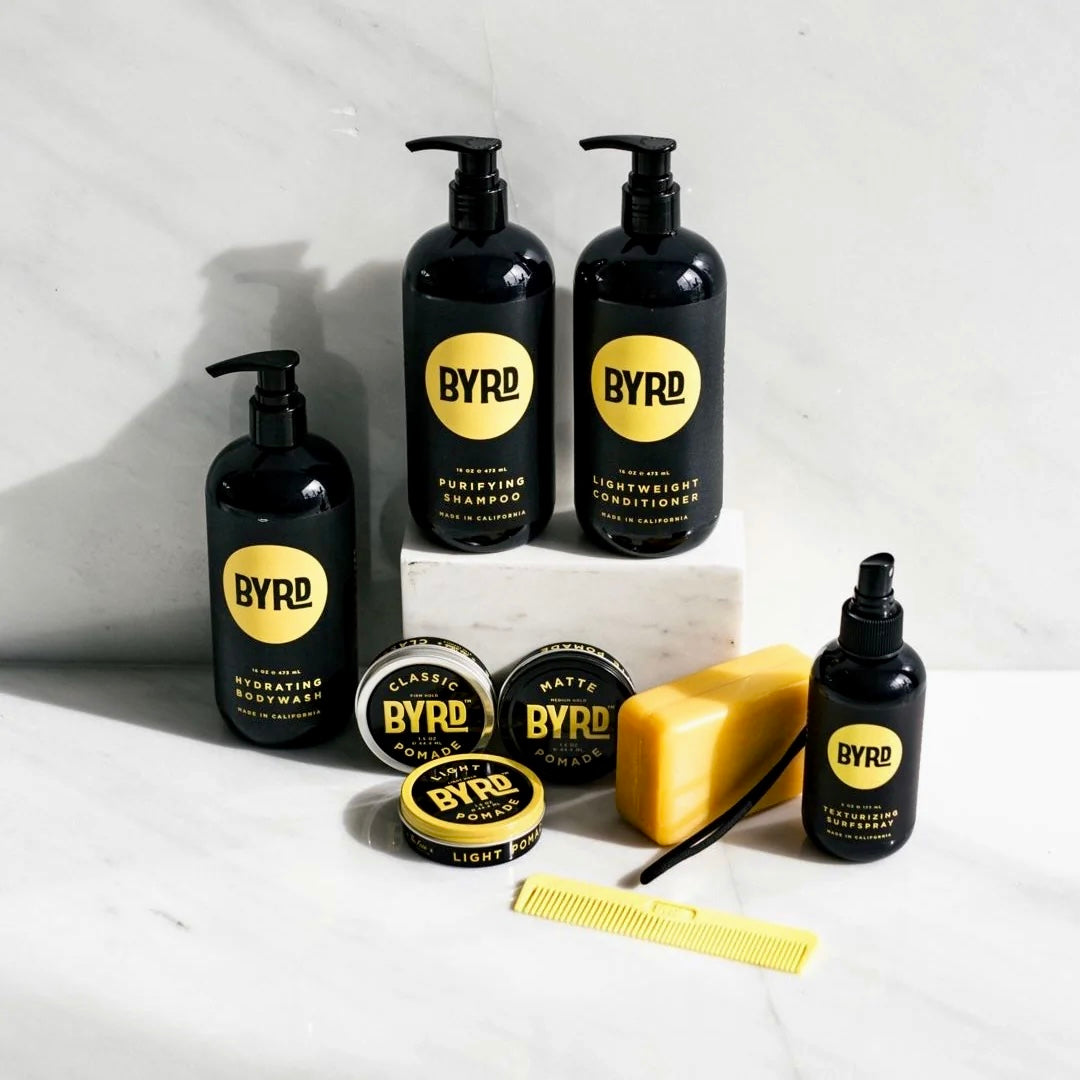 BYRD haircare and styling products arranged on a grey surface