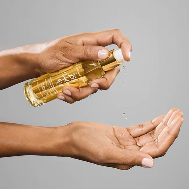 Hand holding a gold bottleBumble and bumble Styling Oil lightweight hair oil with heat protectant for frizz and shine in Canada