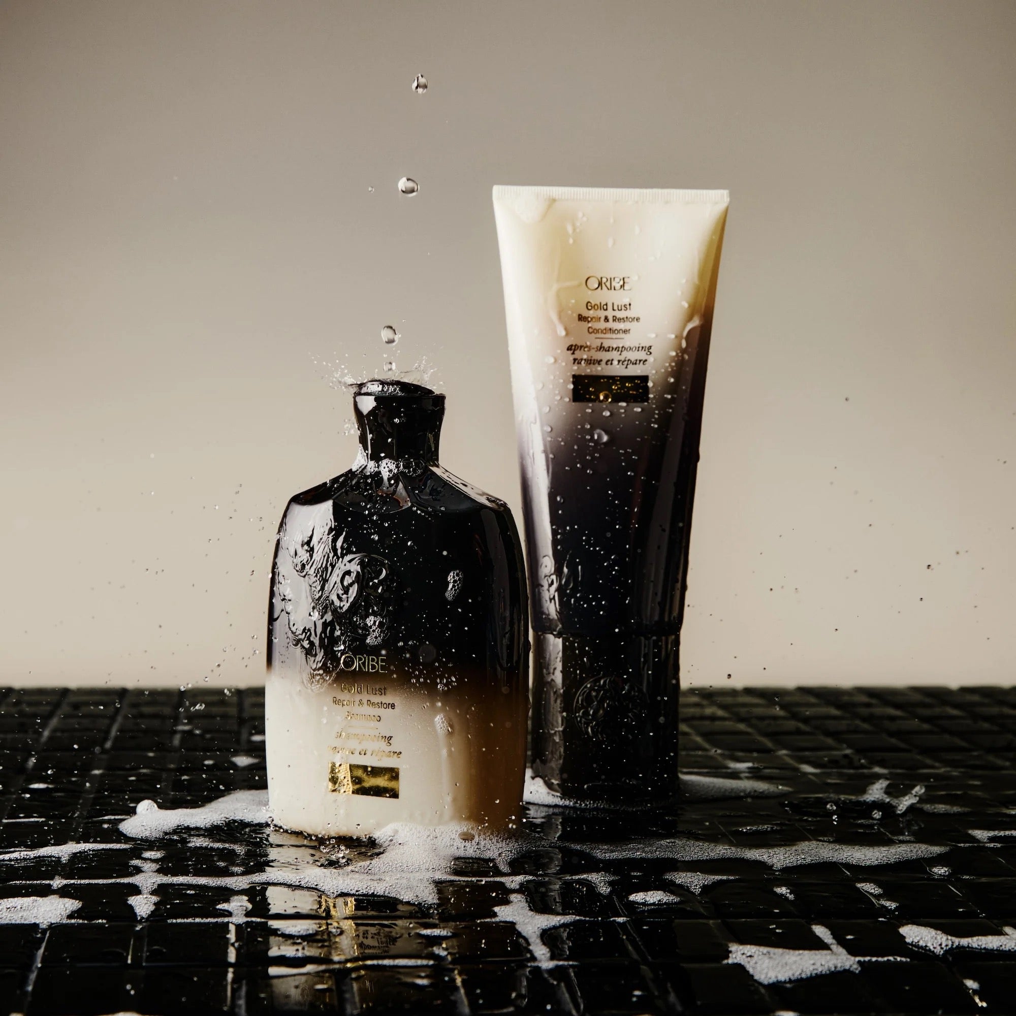 Oribe Gold Lust Repair & Restore Shampoo bottle for damaged hair repair and luxury Oribe haircare on a textured surface with water droplets.