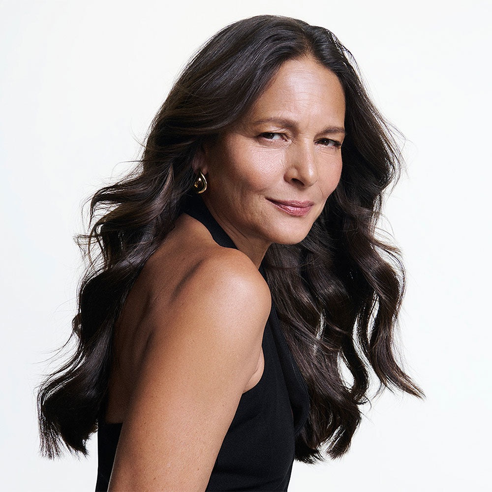 Woman with long dark hair wearing a black sleeveless top on a white background
