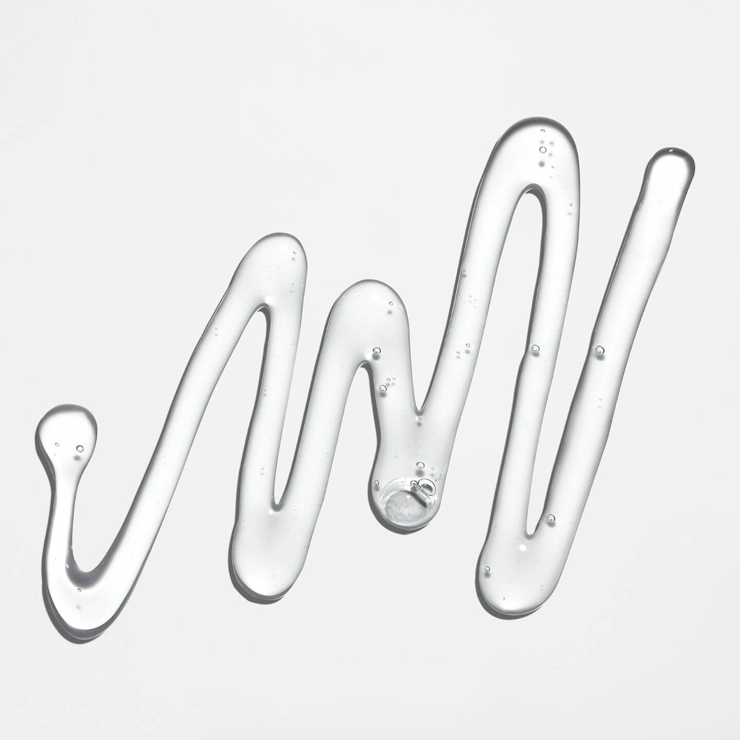 Three droplets of clear liquid arranged in a wavy pattern on a light gray background