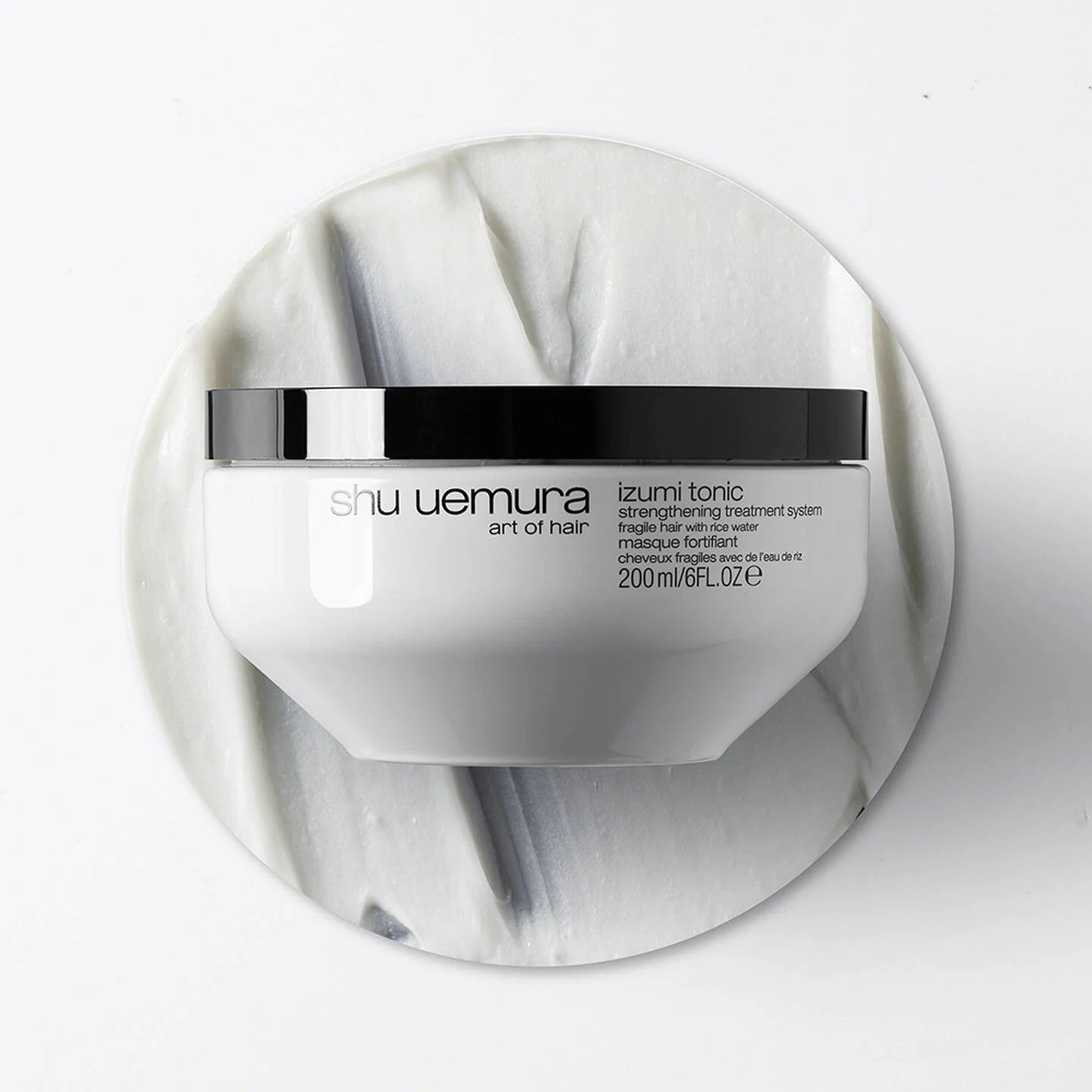 Shu Uemura hair product container on a white marble background