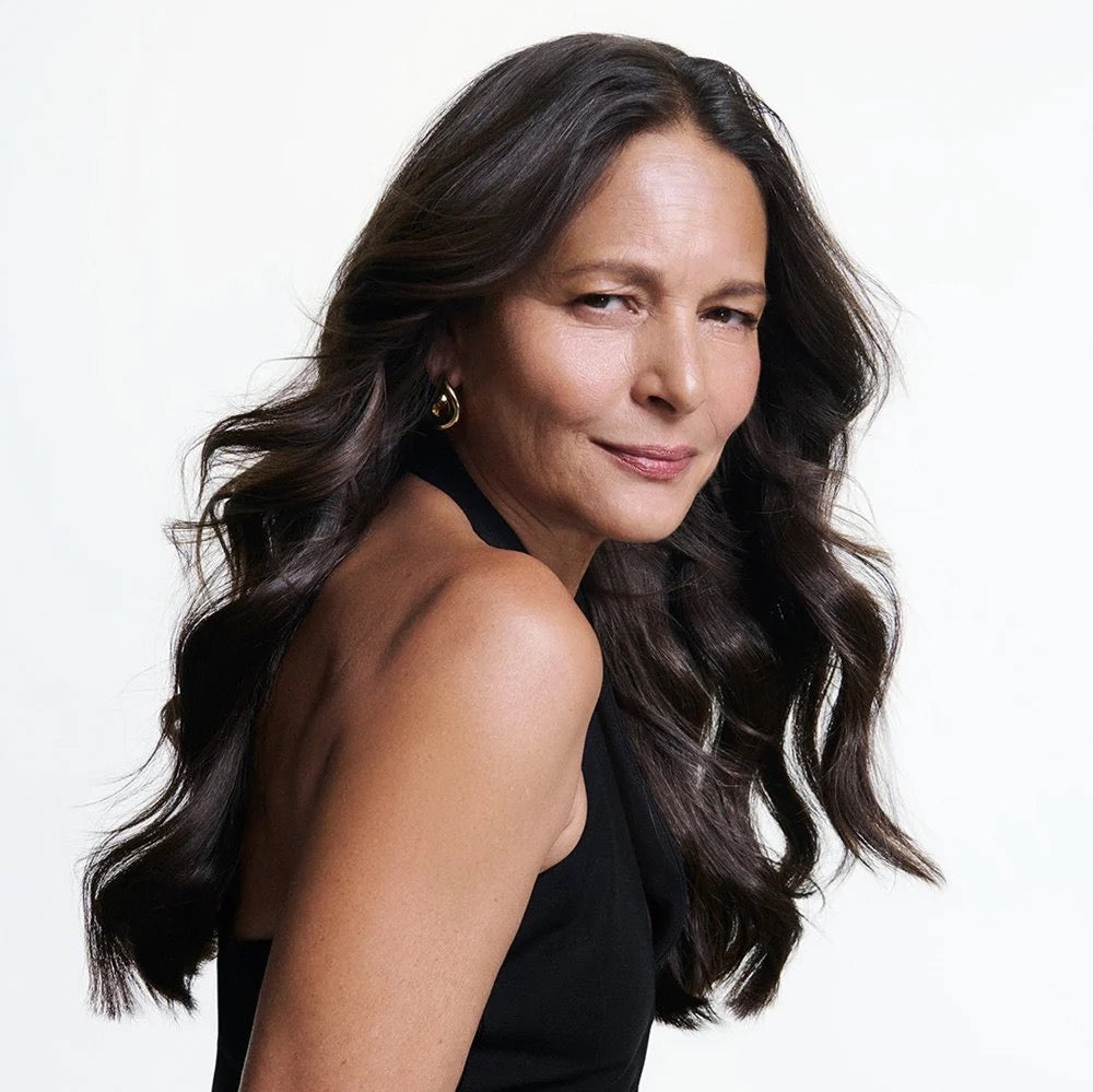 Woman with long dark hair wearing a black sleeveless top on a white background