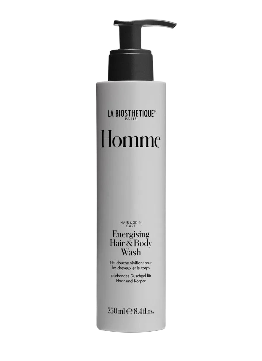 A tall cylindrical pump bottle of La Biothetique Homme Energising Hair & Body Wash, featuring a light gray body and a black pump dispenser, set against a clean white background.