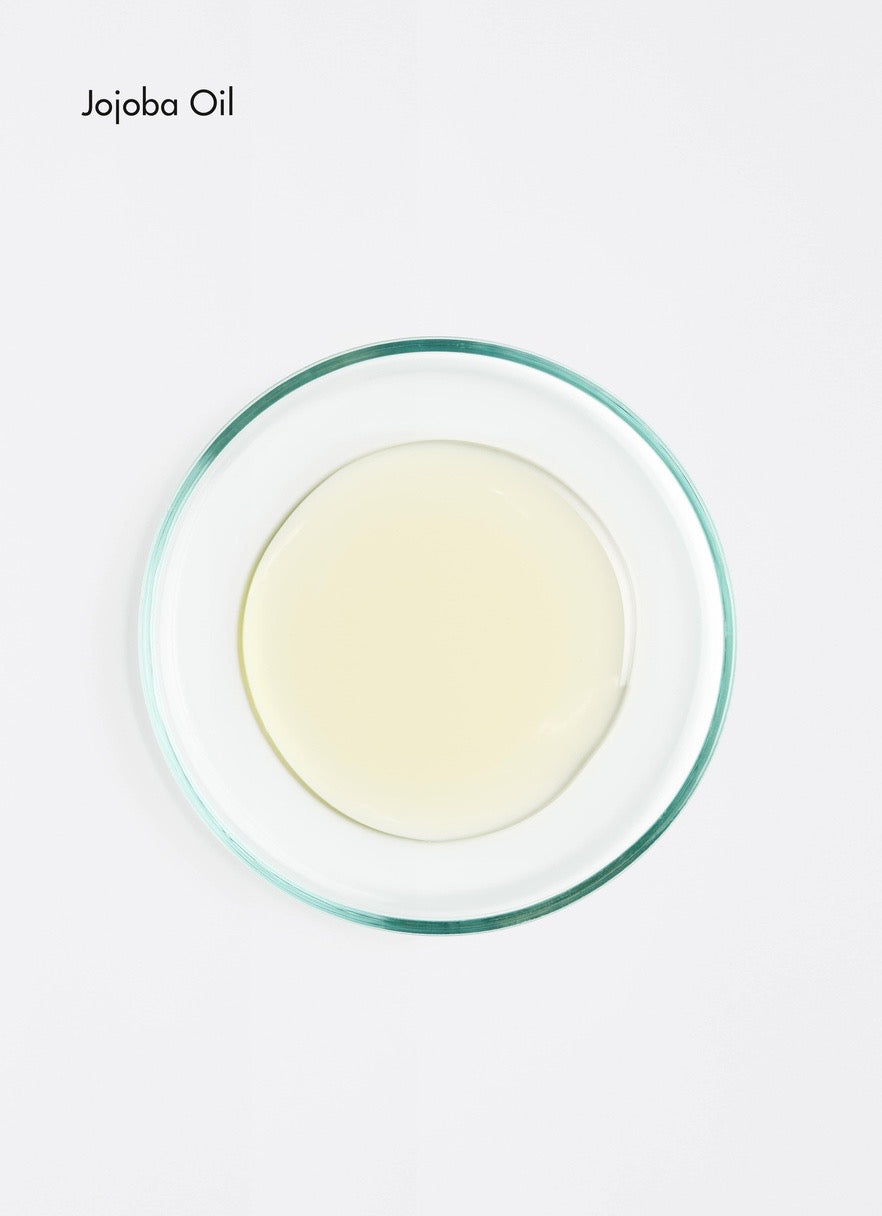 Jojoba oil in a glass container on a white background