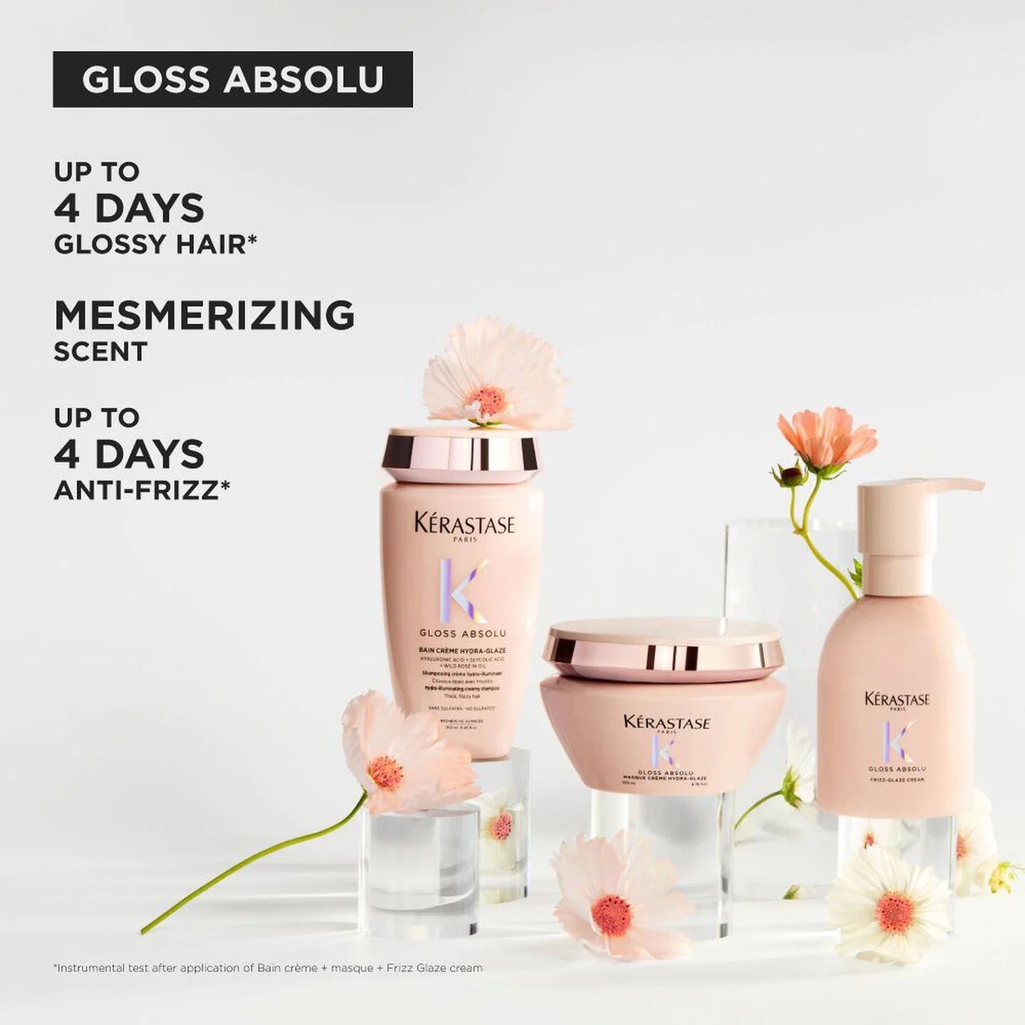 Kérastase Shine Absolu glossy hair cream and anti-frizz care set in soft blush pink packaging with rose gold lids, styled with pink flowers on a clean white background with promotional text.