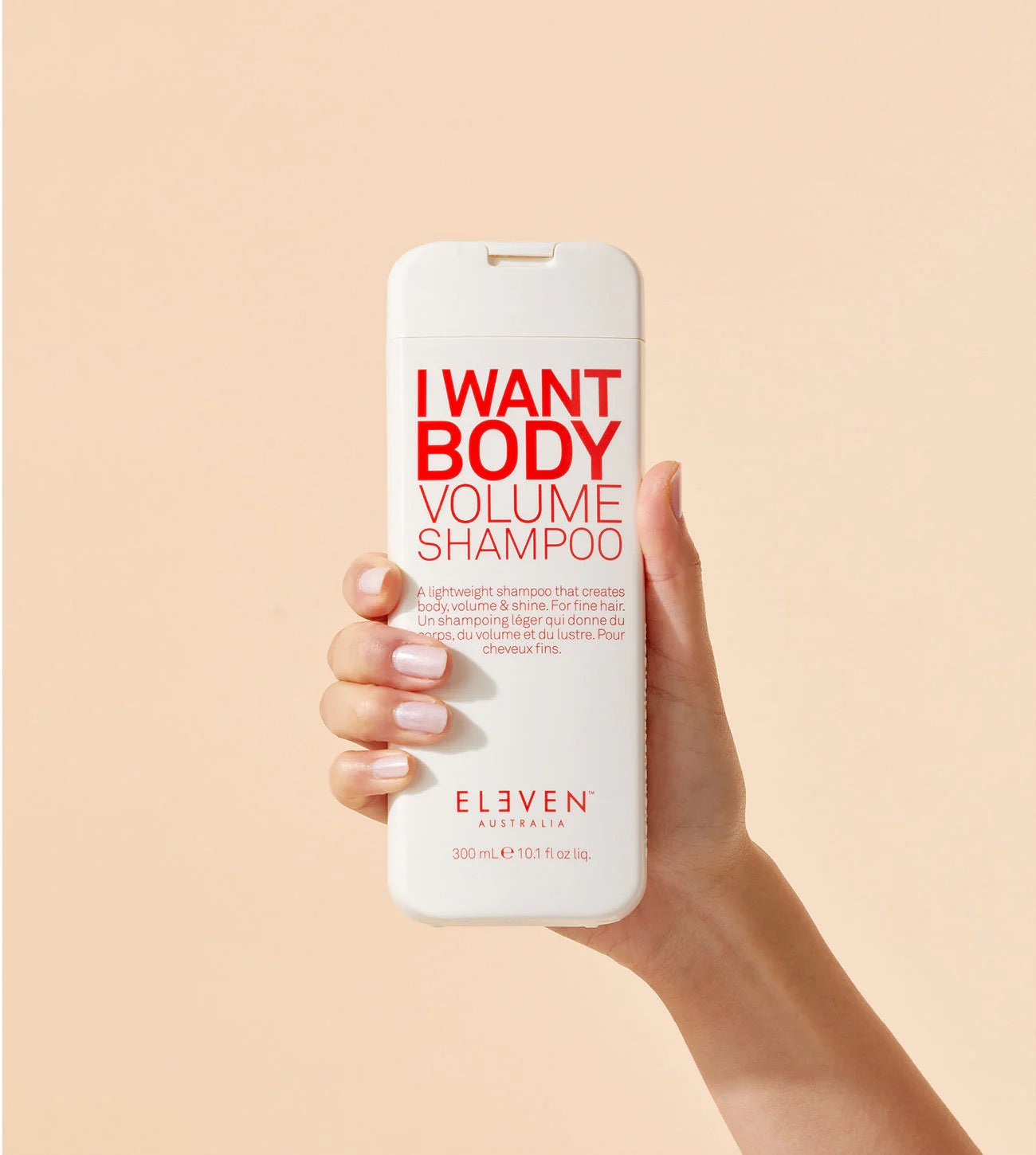Hand holding a bottle of ELEVEN Australia I Want Body Volume Shampoo bottle for fine, flat hair and lightweight volume curious Salons Canada