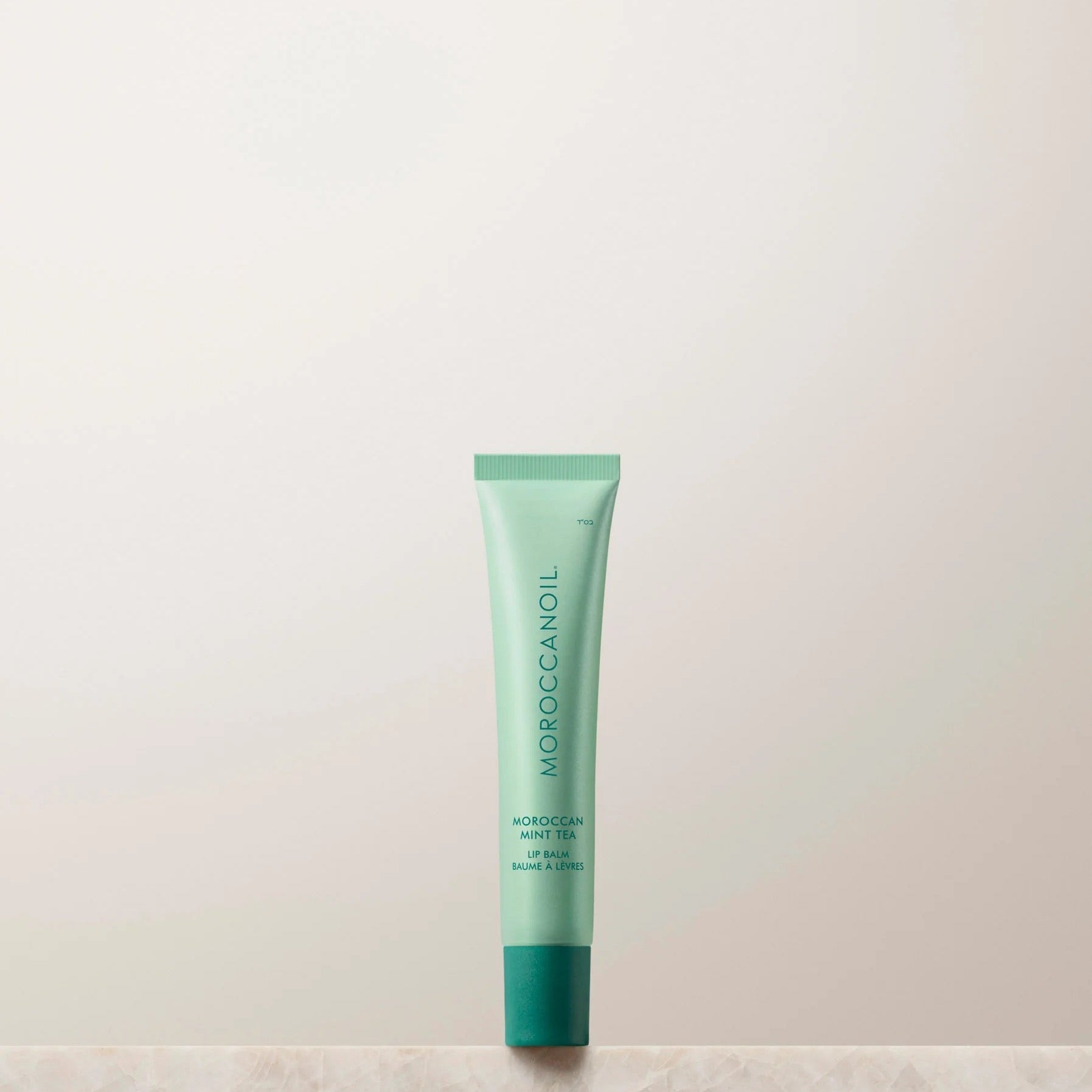 Moroccanoil lip balm tube on a light background