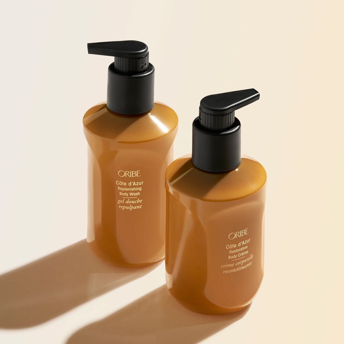 Two Oribe body wash bottles on a beige background available at Curious Salons