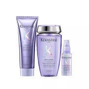 Three Kérastase Paris haircare products in a coordinated lavender-purple colorway on a white background: a long cream bottle, a larger bottle with a silver cap, and a small spray bottle.