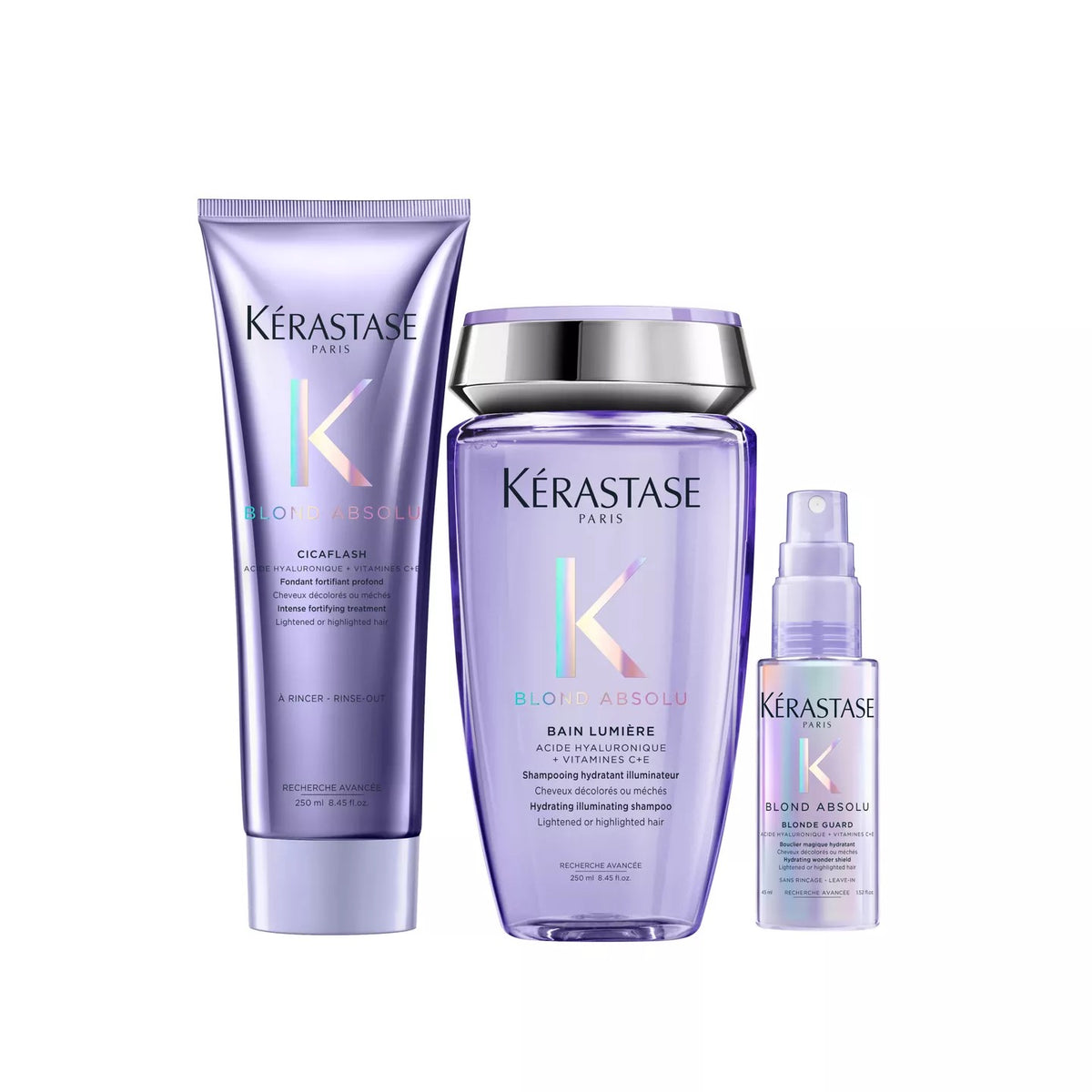 Three Kérastase Paris haircare products in a coordinated lavender-purple colorway on a white background: a long cream bottle, a larger bottle with a silver cap, and a small spray bottle.