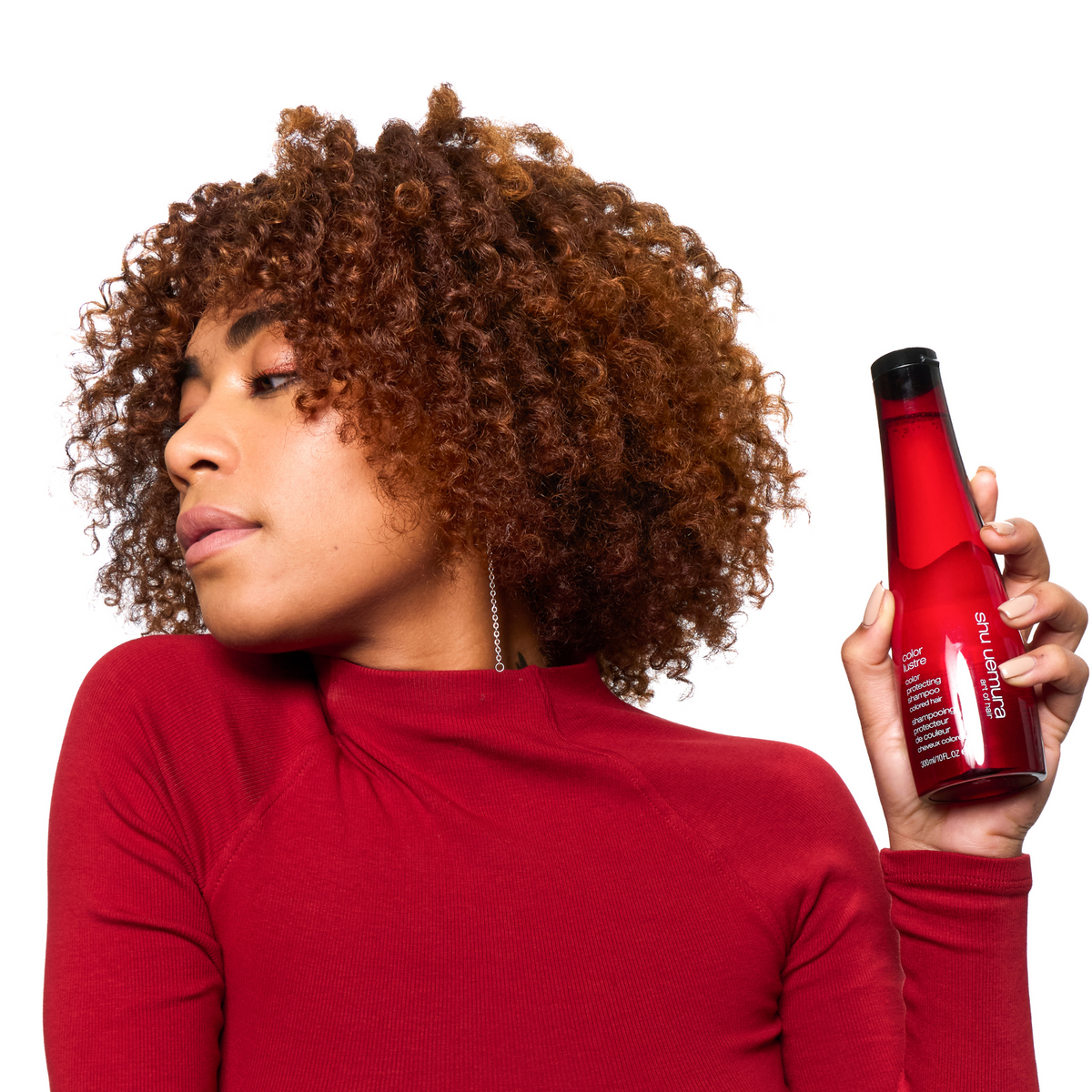 Woman holding a red bottle with a white label against a white background