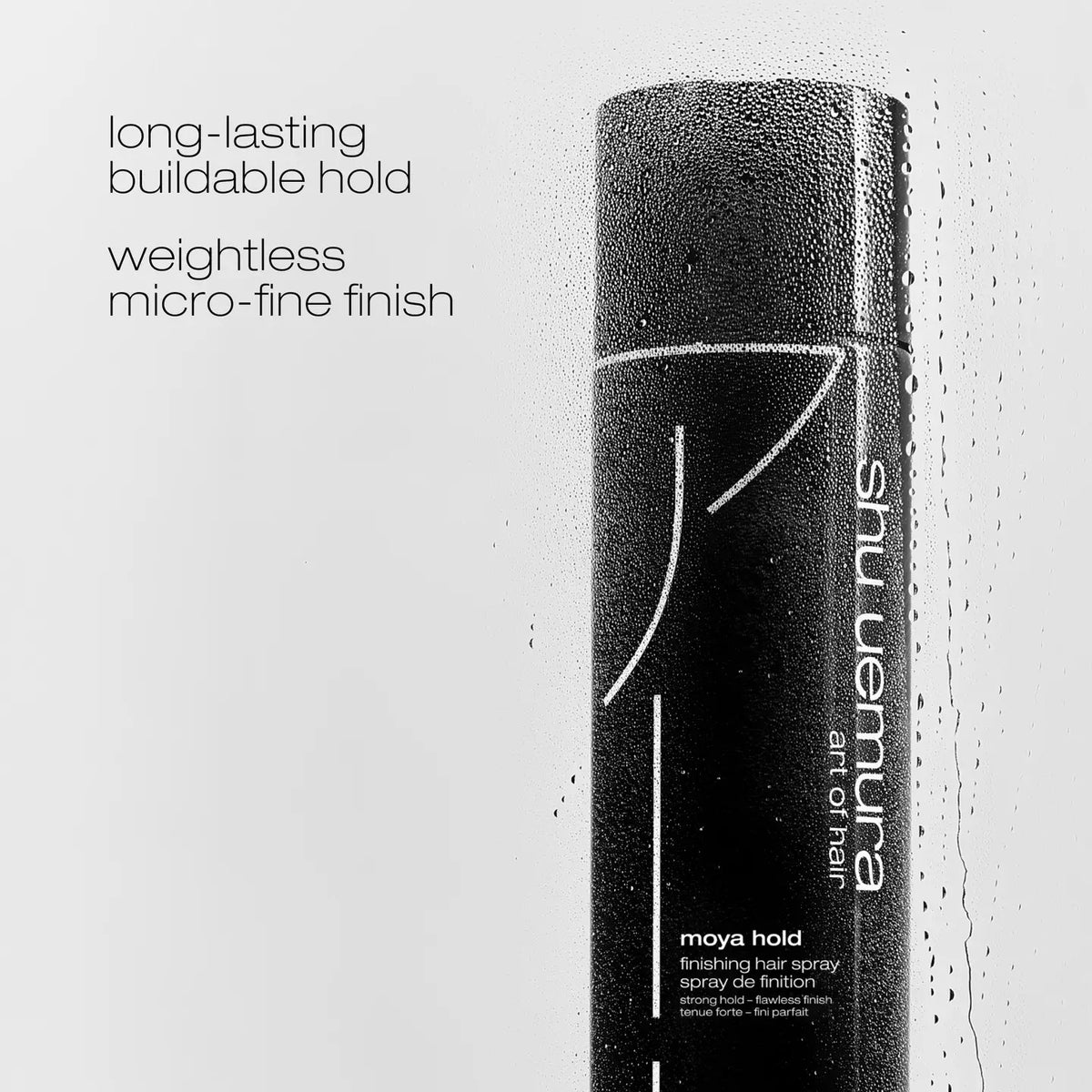 Shu Uemura Maya Hold finishing hair spray in a matte black cylindrical bottle with white text, shown against a light gray background with water droplets and marketing text on the left.