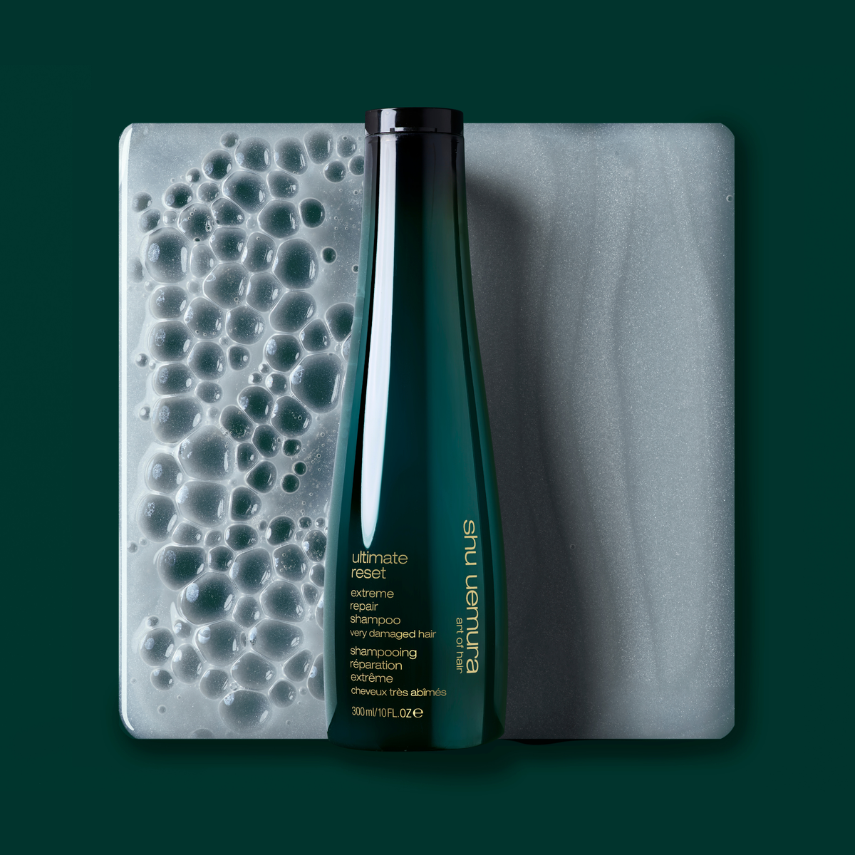 Shu Uemura Ultimate Reset bottle with a textured bar of soap on a dark green background