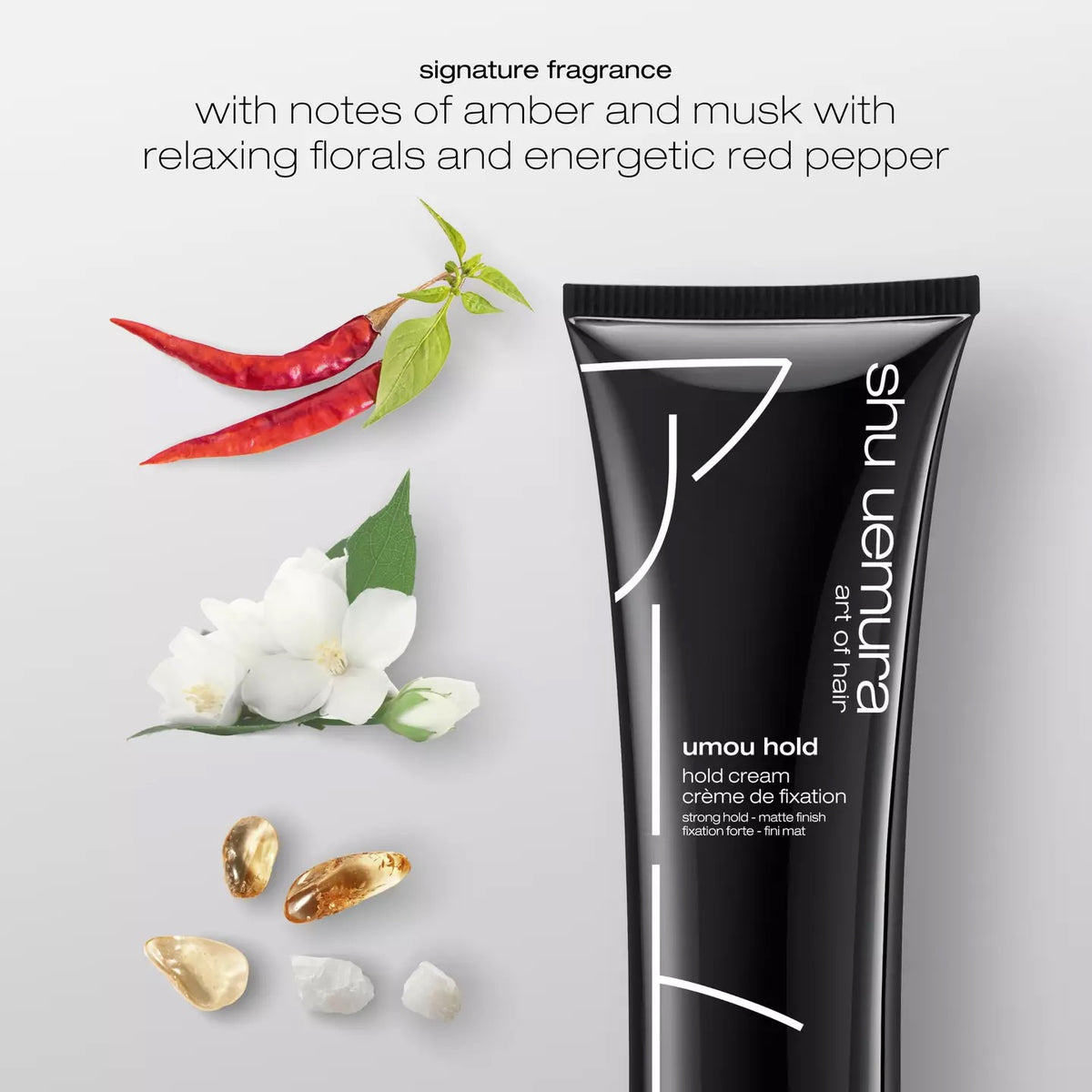 Shu Uemura hair product with flowers, peppers, and stones on a light gray background