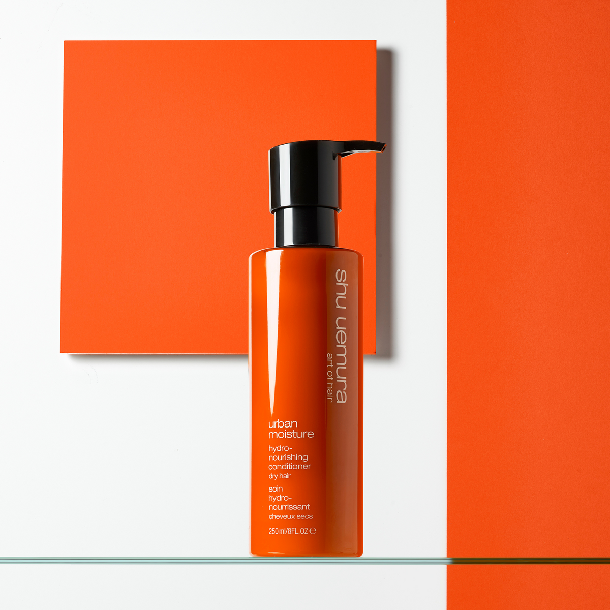 Shu Uemura hair product on a white background with orange accents