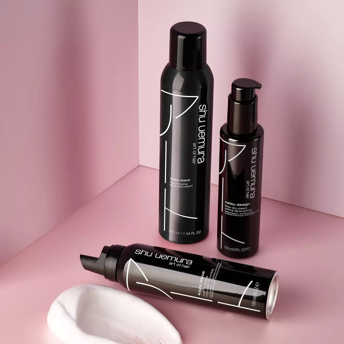 Shu Uemura Wata Wave Texturizing Spray products on a pink background at Curious Salons Calgary Canada