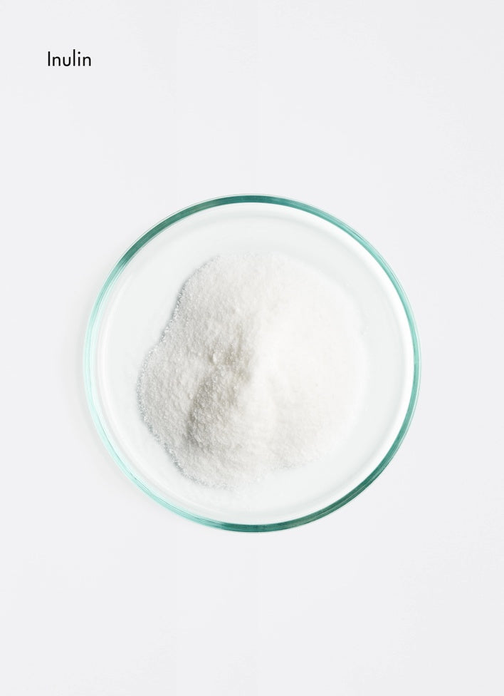 Inulin powder in a glass container on a white background